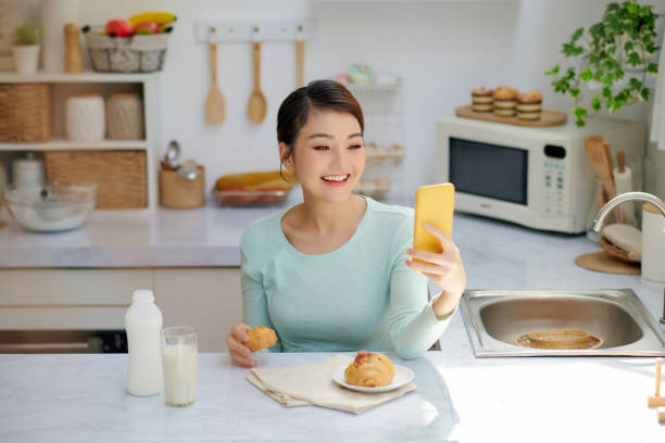 istock Woman Eating Breakfast Whilst Using Mobile Phone 1326748519