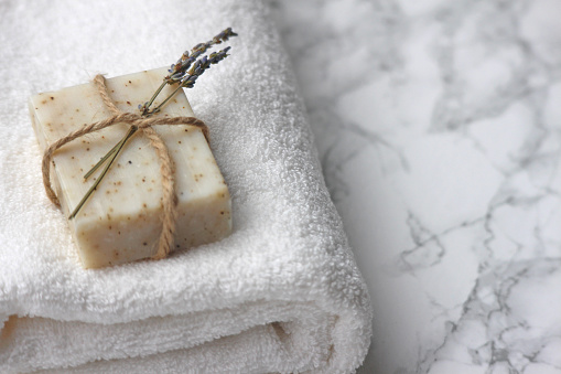 A bar of organic homemade soap on a fresh white towel. Hotel/B&B bathroom theme.