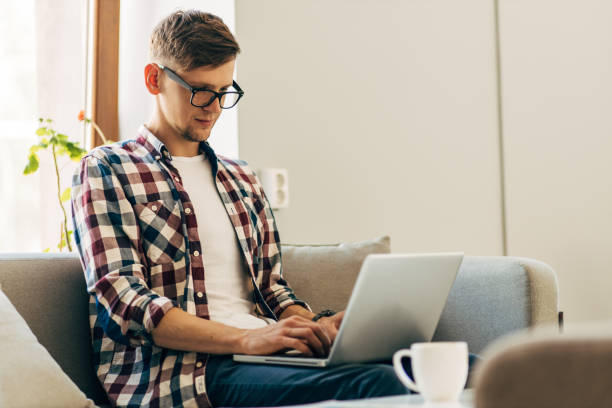 istock Young man wearing glasses using laptop typing text on keyboard chatting, successful freelancer working online on computer at home 1326754906