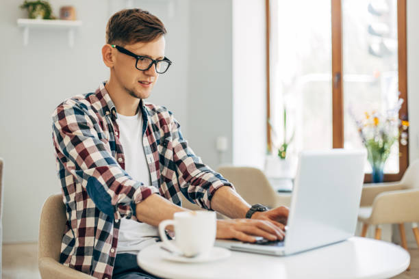 istock young man sitting at his table in a cafe, Young handsome businessman using laptop, working while sitting at the table 1326755211