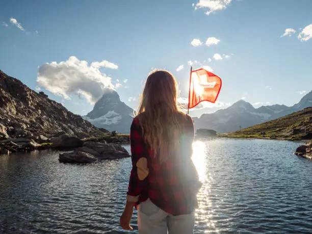 Female holding Swiss flag against the mountain landscape with the Matterhorn peak