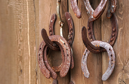 Old worn rusty horseshoes displayed on wall of stables - visitors can take them as luck symbol