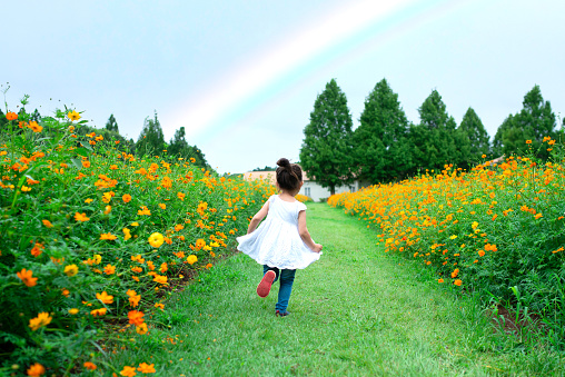 Little girl running towards the rainbow