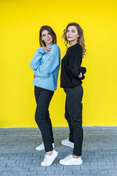 istock girlfriends posing together in modern knitted sweaters isolated on yellow wall studio portrait 1326760390