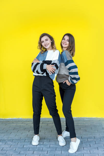 istock girlfriends posing together in modern knitted sweaters isolated on yellow wall studio portrait 1326761581