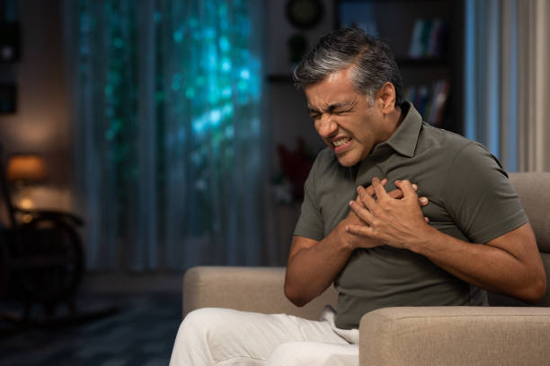 shot of a mature men sitting on sofa at home:- stock photo Adult, adult only, India, Indian ethnicity, mature men heart attack stock pictures, royalty-free photos & images