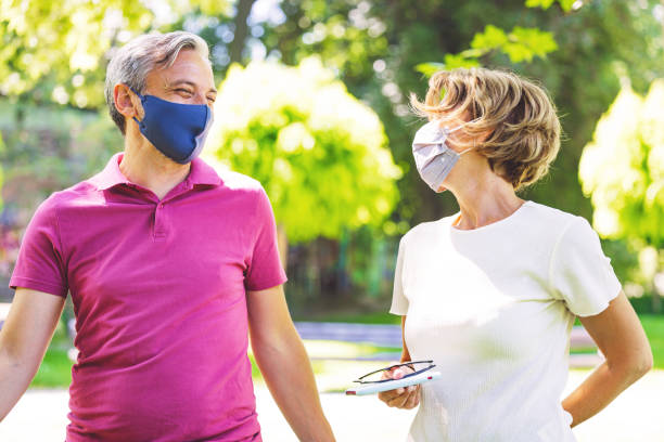 istock Senior couple wearing mask strolling in the park 1326762397