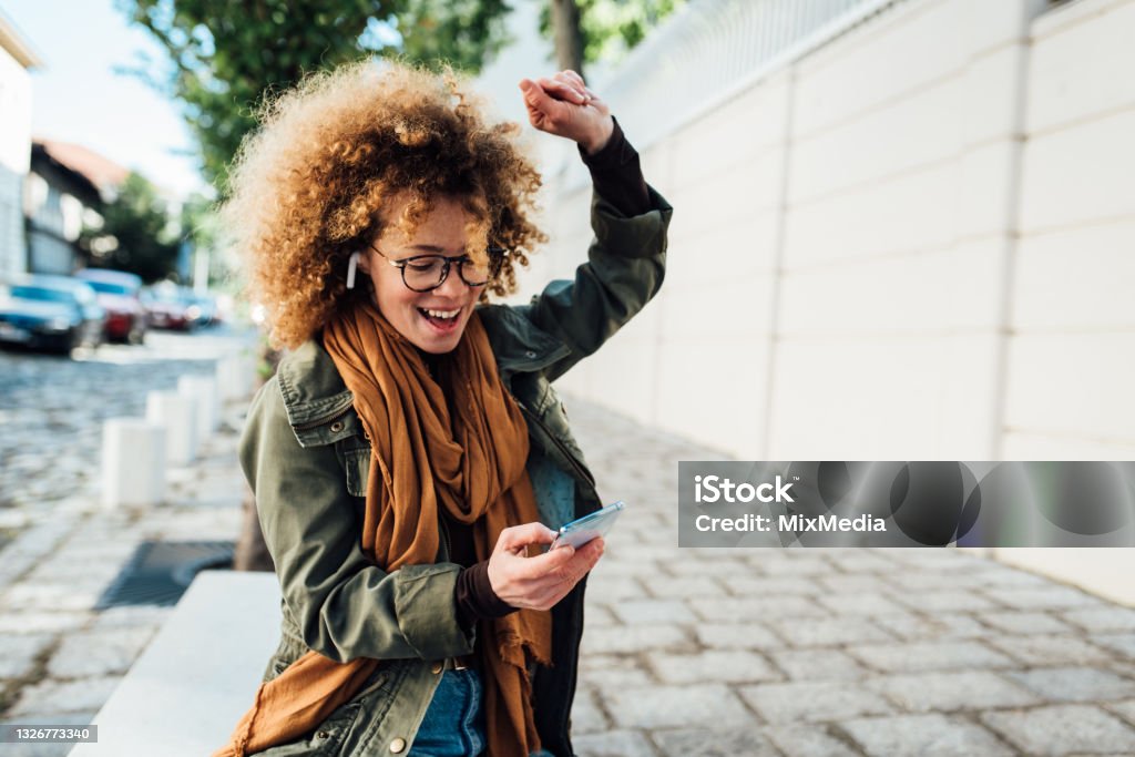 Portrait of a happy girl dancing with her favorite song Portrait of a beautiful young woman enjoying outdoors and listening to music. Excitement Stock Photo