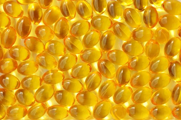 vitamin-d-kapseln nahals gelbem hintergrund auf einem vollen rahmen - cod liver oil fish oil vitamin e vitamin pill stock-fotos und bilder