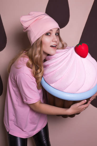 istock Pleased young blonde model posing with big cupcake sweet decoration 1326778904