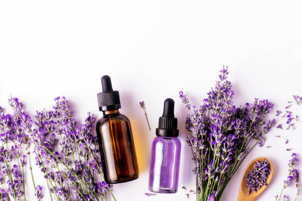 istock Bottled lavender essential oil and lavender sprigs on white background with copy space, top view. Spa concept. 1326779854