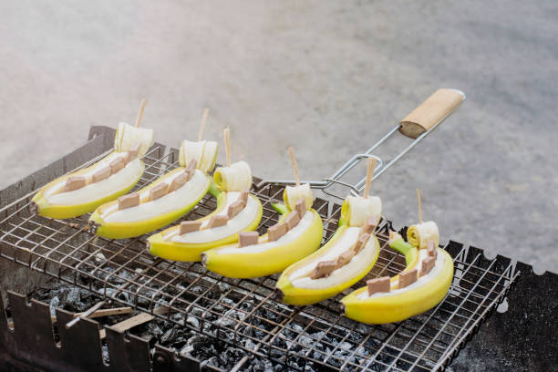 банановый десерт на гриле. бананы с шоколадом на углях. - grilled bananas стоковые фото и изображения