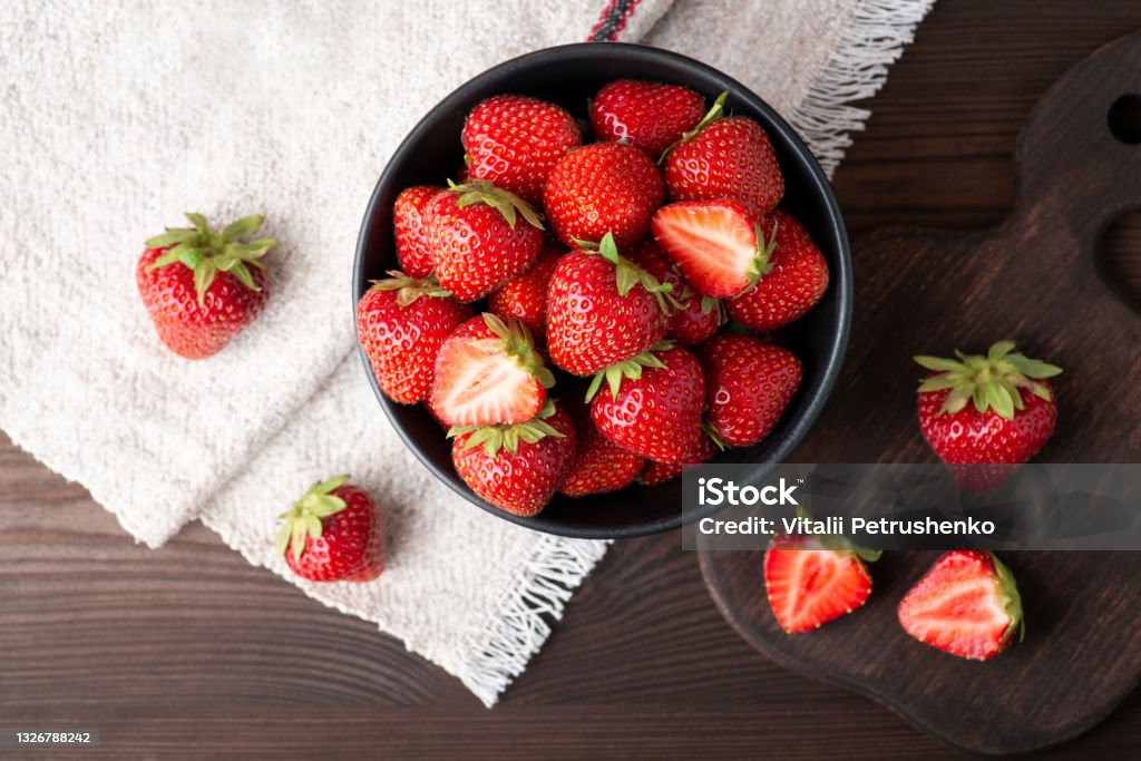 Top-down photo of many strawberries on dark table with a white natural linen towel in the corner Beautiful composition with strawberry as a main object Strawberry Stock Photo