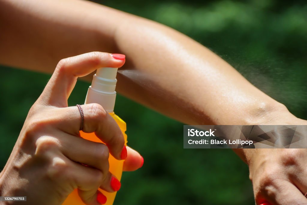 Person spraying mosquito insect repellent in the forest, insect protection Insect repellent against mosquitoes, ticks. Skin protection against tick and other insect. Bug spray anti insects. Woman spraying insect repellent using yellow spray bottle. Insect Repellant Stock Photo
