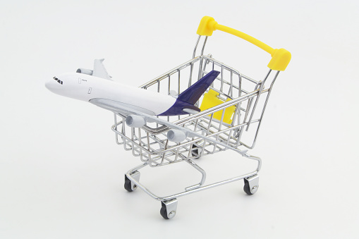 Airplane model in shopping cart. Buy air tickets and travel tour concept.