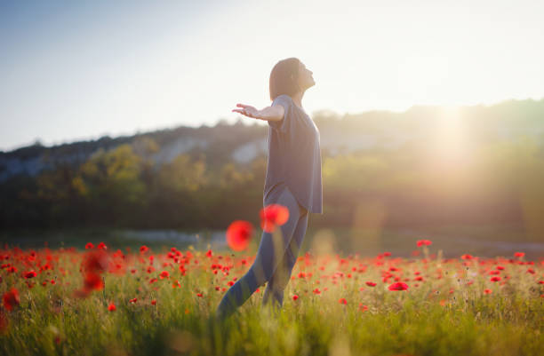Young beautiful woman with raised arms in spring poppy field. Soft colors. pensive relaxed atmosphere.