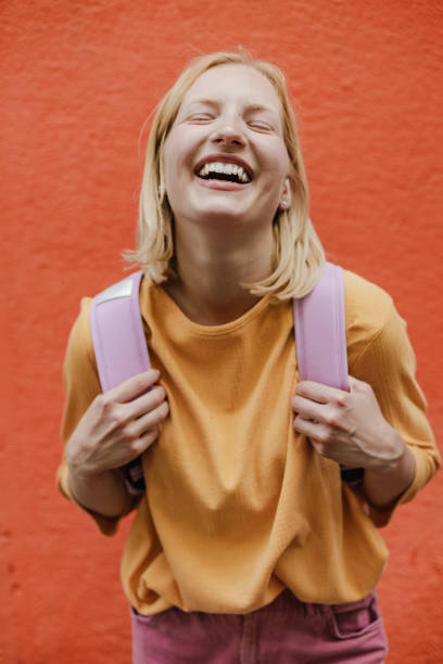 retrato de uma jovem na rua em frente à parede laranja - tourist backpack smiling cheerful - fotografias e filmes do acervo