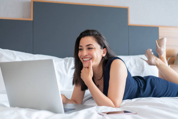 istock Businesswoman Lying On Bed And Working On Laptop While Using Smartphone İn Hotel Room 1326808098