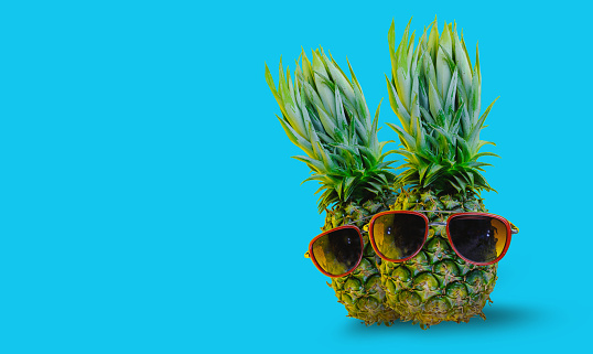Pineapple wearing red sunglasses on isolated blue background