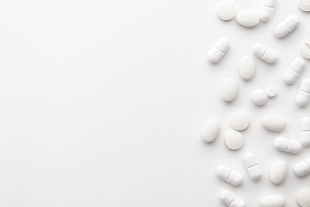 istock Scattered white pills on a white background. Bright monochrome composition. Pharmacology 1326811234