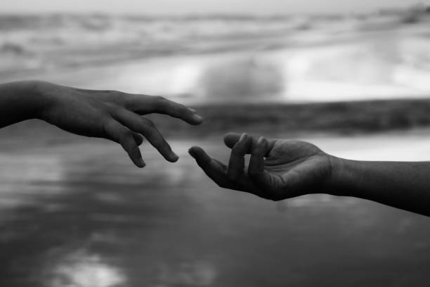 Helping hands reaching out each others in black and white abstract art background. Humanity concept.