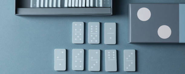 istock Light Blue wood domino pieces on light blue background. Leisure games concept. 1326819434
