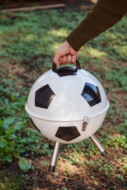 istock Hand carries round barbecue over green lawn 1326819588