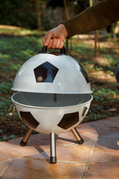 istock Hand open lid on round grill in yard 1326819605