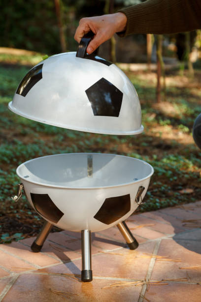 istock Hand open lid on round grill in yard 1326819628