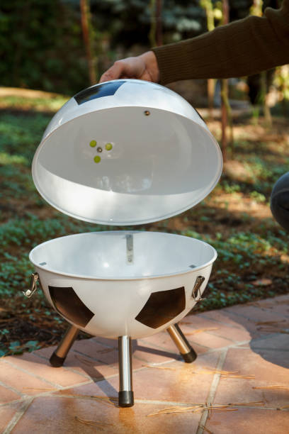 istock Hand open lid on round grill in yard 1326819648