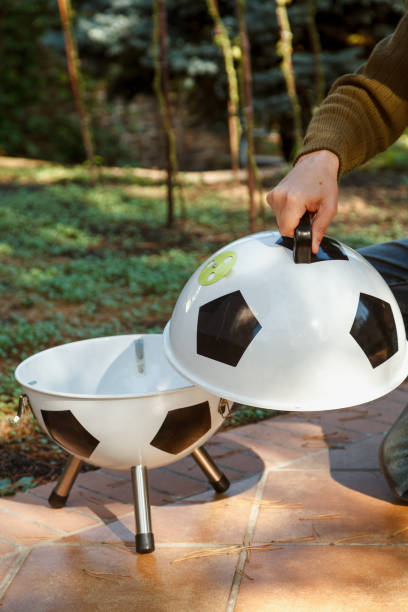 istock Hand open lid on round grill in yard 1326819679