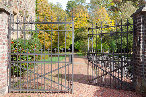 An aged and dilapidated gateway driveway. \nA green and historical background.