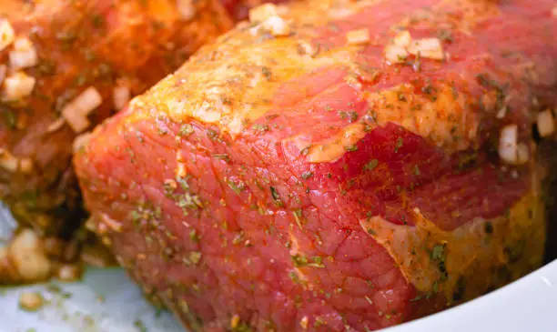 Carne bovina - Lagarto ( Eye round Steak ), Brazilian food. Piece of raw meat seasoned in a large bowl, which is being prepared to be roasted.