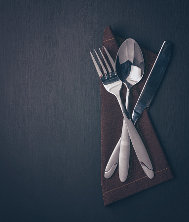 cutlery set-fork, spoon, knife, on dark wood. Minimalistic still life, stylish tableware. close-up of the kitchen decoration and table settin. Top view, copy space. Flat lay.
