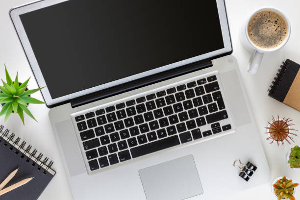 istock Home office. An open laptop on a white desk. Coffee, notebook and plants. View from above. 1326824471