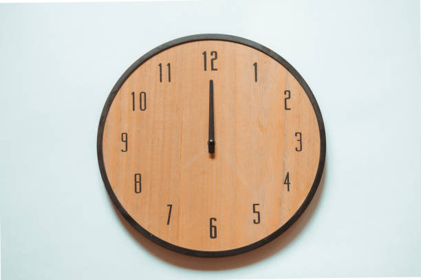 istock Wooden wall clock with black numerals and black hands showing twelve o'clock. 1326827809