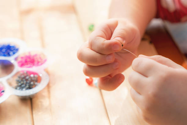 istock The child makes jewelry with his own hands, stringing colorful beads on a thread 1326831920