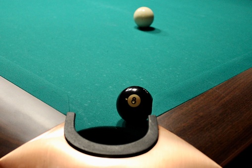 Black billiards ball near with hole