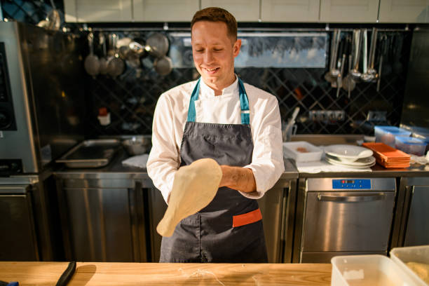 istock Smiling man chef at kitchen skilfully makes pizza base 1326834972