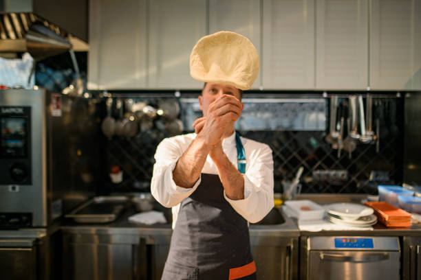 istock Male chef tossing pizza dough in the air 1326835031