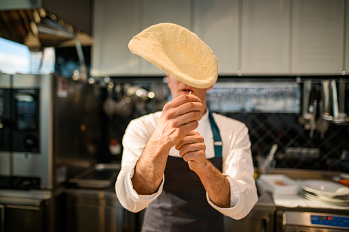 selective focus on the dough that the chef throws up the air. Process of making a pizza base