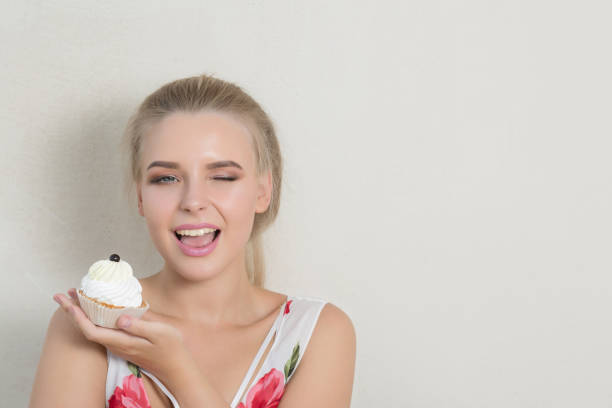 Cheerful blonde girl with perfect makeup holding sweet cream dessert. Space for text