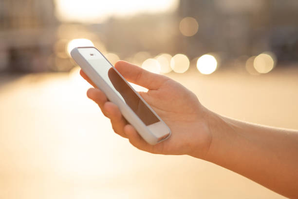 istock Female hand holding cell phone at the blur light background. Space for text 1326840830