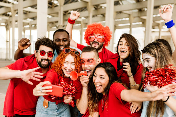 Group of multiracial supporter sport fans taking selfie with mobile phone while supporting their football team - Young people having fun outside the stadium after sport event - Sport entertainment and championship concept grupo de aficionados multirraciales aficionados al deporte tomándose selfie con el teléfono móvil mientras apoyan a su equipo de fútbol - jóvenes divirtiéndose fuera del estadio después de un evento deportivo - entretenimiento deportivo y concepto d