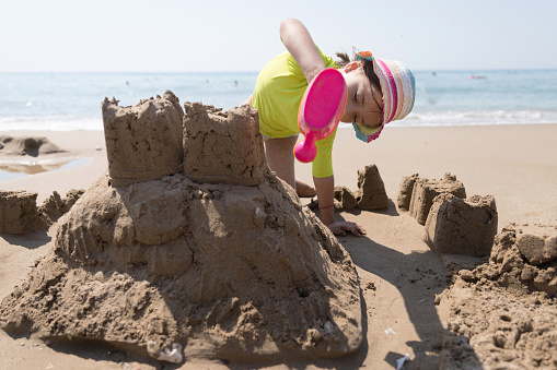 Child making sandcastles and using watering pot