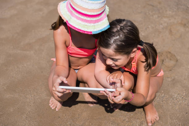 istock Happy children using tablet to surf the internet on the beach 1326850616