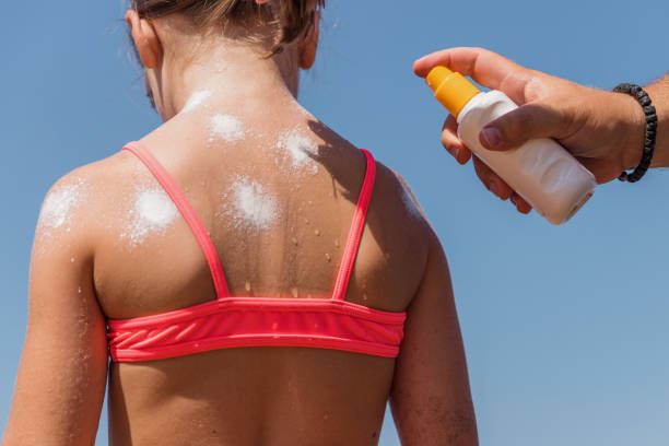istock Girl having sunscreen applied on her back 1326850654