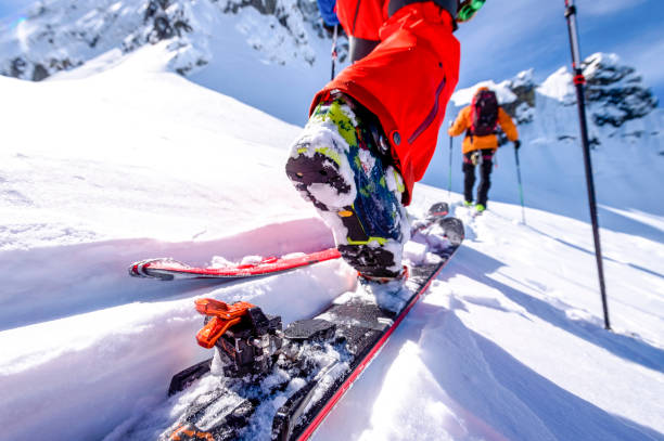 POV of backcountry skiers climbing snow slope View past skis of man to friend skiing ahead back country skiing photos stock pictures, royalty-free photos & images