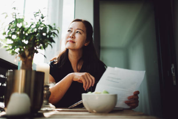 mulher sênior asiática trabalhando em casa com um laptop - uk check finance home finances - fotografias e filmes do acervo