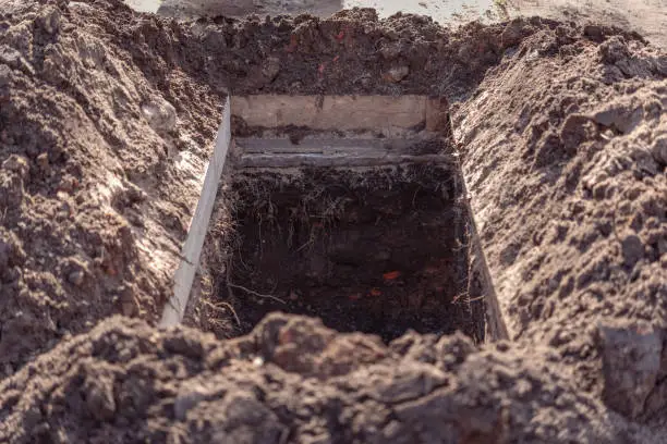 Photo of Freshly dug grave pit at cemetery, a close-up